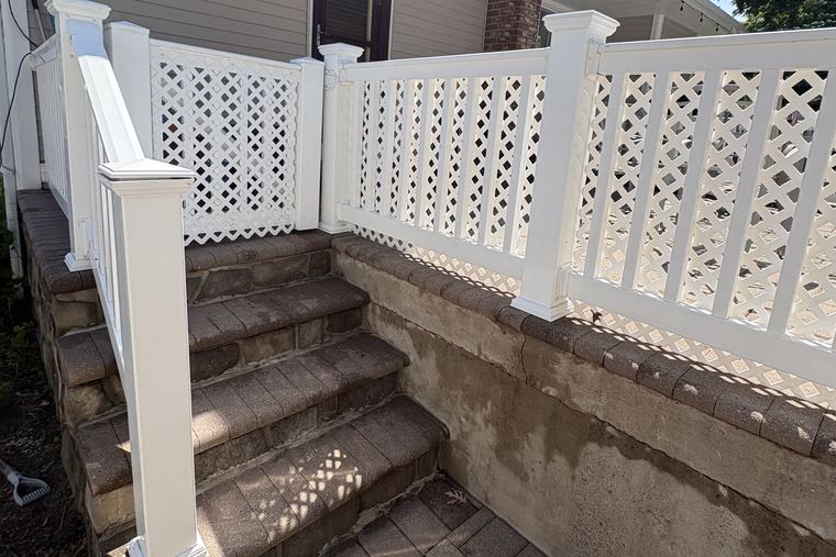 Clean stone steps and white lattice railing on a Long Island home