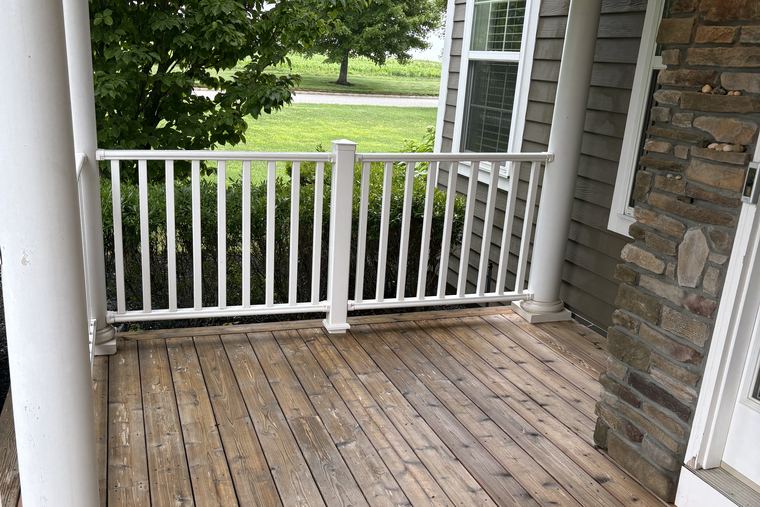 A clean covered porch with white railings and a stone column on a North Fork home