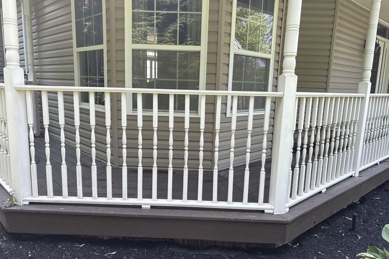 White spindle railing around a bay window, cleaned bright white after soft washing