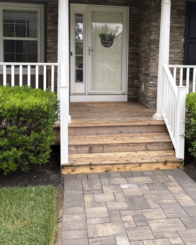 A clean paver walkway leading up to a front porch