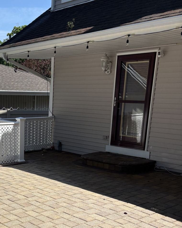 A clean white gutter and downspout running along the roofline of a house